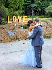 A newlywed couple in front of LOVE sign.